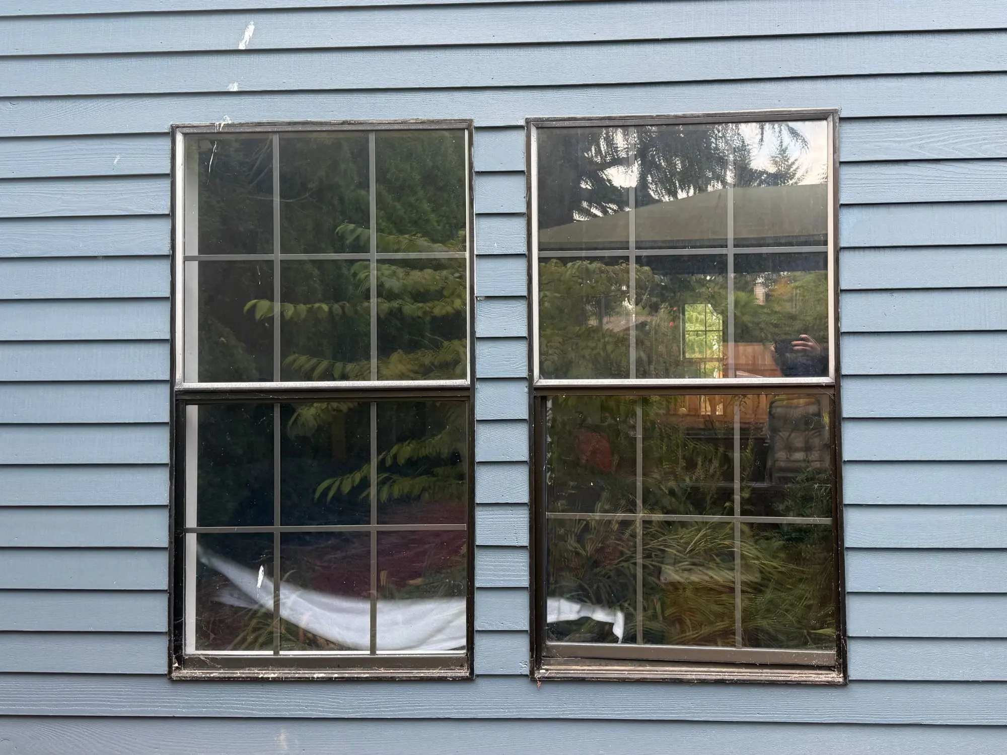 The same two openings before replacement, with old dark-framed windows and grilles